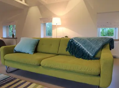 a green couch with two pillows on it in a living room at Villa de Hazelaar in Schoorl