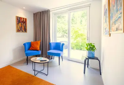 a room with two blue chairs and a window at Villa de Hazelaar in Schoorl