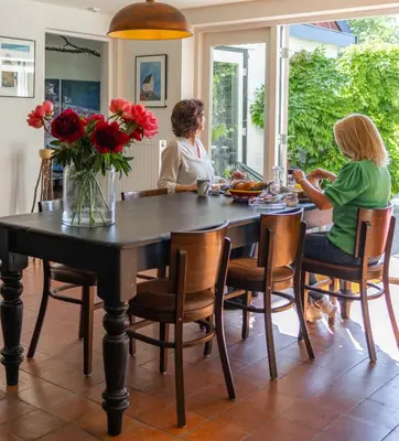 two women sitting at a table in a dining room at Villa de Hazelaar in Schoorl