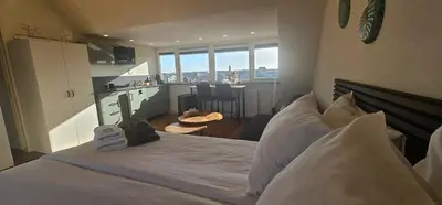 a bedroom with a large white bed and a kitchen at Sunnyzandvoort in Zandvoort