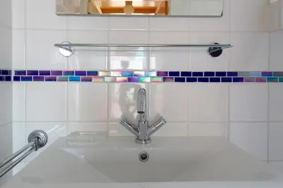 a bathroom sink with a faucet and tiles on the wall at Centre beach lodge in Zandvoort