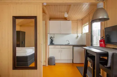 a small kitchen with white cabinets and a mirror at Centre beach lodge in Zandvoort