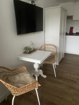 a white table with two chairs and a television on a wall at Pension Hendriks in Zandvoort