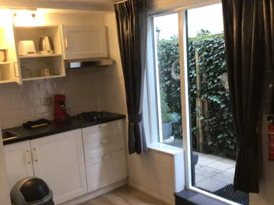 a kitchen with white cabinets and a large window at Pension Hendriks in Zandvoort