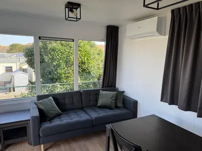 a living room with a couch and a large window at Chalet Duinpan in IJmuiden