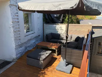 a patio with a couch and a table and an umbrella at Chalet Duinpan in IJmuiden