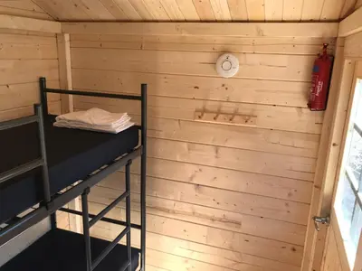 a room with a bunk bed and a clock on a wall at Chalet Duinpan in IJmuiden