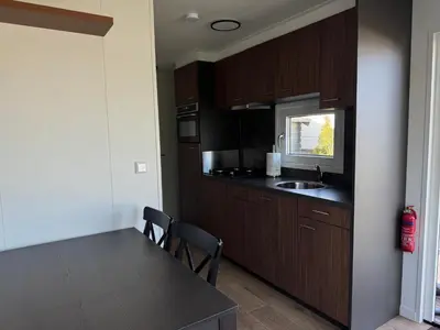 a kitchen with wooden cabinets and a table with chairs at Chalet Duinpan in IJmuiden