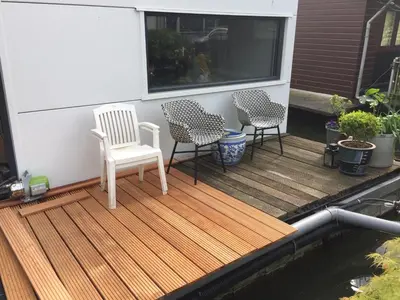 a deck with two chairs and a table and some plants at Reiwa in Amsterdam