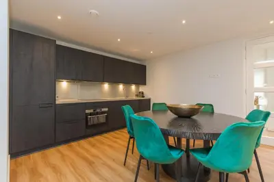 a kitchen with a black table and green chairs at Lage Wurft Beach Apartments in Noordwijk