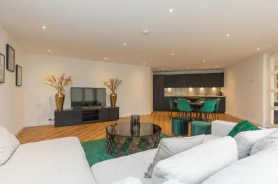 a living room with white couches and a television at Lage Wurft Beach Apartments in Noordwijk