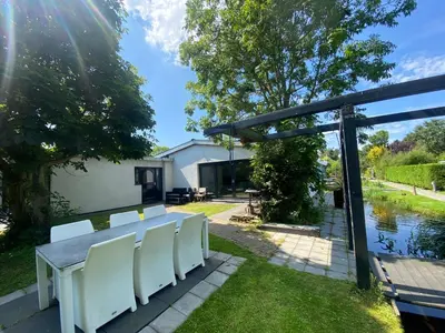 a patio with a table and white chairs at Bungalow Haarlem Amsterdam with jacuzzi in Vijfhuizen