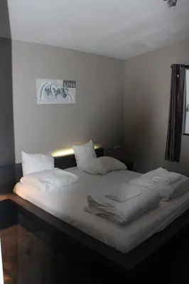 a bedroom with a bed with white sheets and pillows at Bungalow Haarlem Amsterdam with jacuzzi in Vijfhuizen