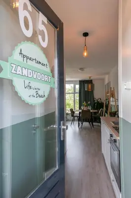 a kitchen and living room with a sign on the door at Amsterdam Beach Apartment 65 in Zandvoort
