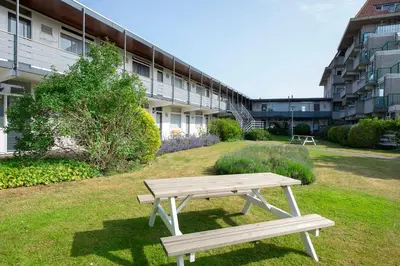a wooden bench sitting in front of a building at Amsterdam Beach Apartment 65 in Zandvoort