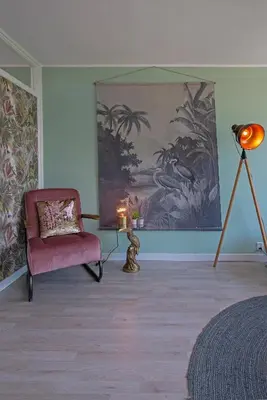 a living room with a chair and a painting at Amsterdam Beach Apartment 65 in Zandvoort