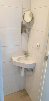 a white bathroom with a sink and a mirror at Egmont op zee in Egmond aan Zee