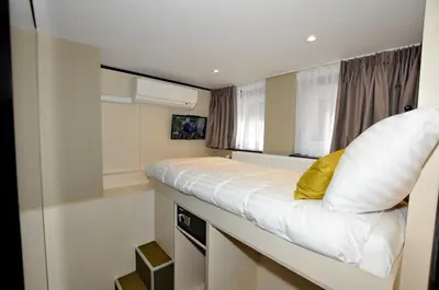 a small bedroom with a white bed with a yellow pillow at Cityview Hotel in Amsterdam