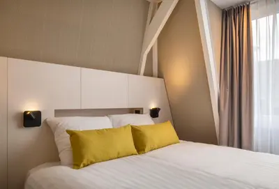 a bedroom with a white bed with a yellow pillow at Cityview Hotel in Amsterdam