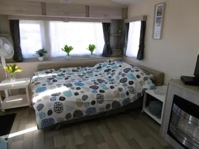 a bedroom with a bed with a blue and white comforter at Chalet Joleen IJmuiden aan zee, vlakbij het strand in IJmuiden