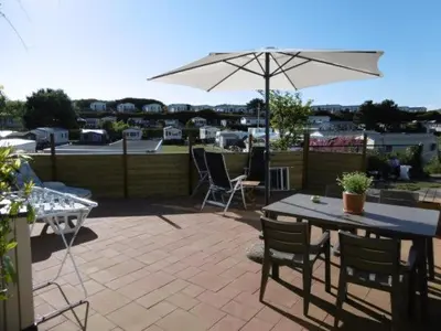 a patio with an umbrella and a table and chairs at Chalet Joleen IJmuiden aan zee, vlakbij het strand in IJmuiden