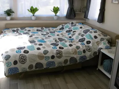 a bed with a comforter on it in a bedroom at Chalet Joleen IJmuiden aan zee, vlakbij het strand in IJmuiden