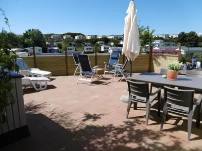 a patio with chairs and a table and an umbrella at Chalet Joleen IJmuiden aan zee, vlakbij het strand in IJmuiden