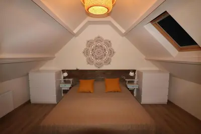 a attic bedroom with a bed with orange pillows at De Strandmus in Egmond aan Zee