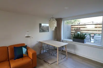 a living room with a couch and a table and a window at De Strandmus in Egmond aan Zee