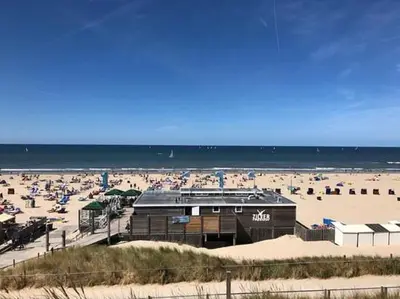 a beach with a building and a lot of people at De Strandmus in Egmond aan Zee