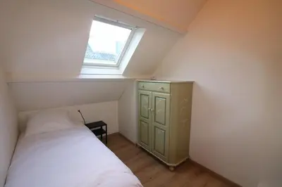 a small bedroom with a bed and a window at De Strandmus in Egmond aan Zee