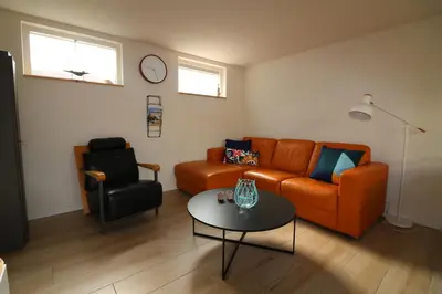 a living room with an orange couch and a table at De Strandmus in Egmond aan Zee