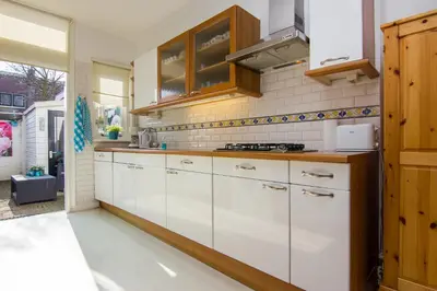 a kitchen with white cabinets and a stove at Happy Home in Zandvoort