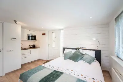 a bedroom with a bed with pillows and a kitchen at Studio 4 u with private parking in Zandvoort