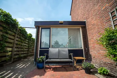 a chair sitting on a patio next to a brick building at Studio 4 u with private parking in Zandvoort