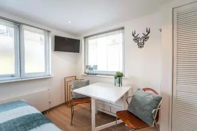 a bedroom with a desk and a bed and windows at Studio 4 u with private parking in Zandvoort