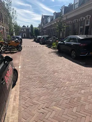 a cobblestone street with cars parked on it at Poelgeeststraat in Leiden