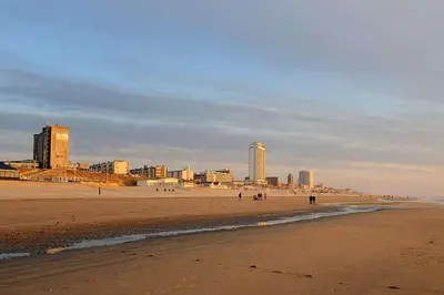 a beach with people walking on the sand and buildings at Continentaiz Appartement in Zandvoort