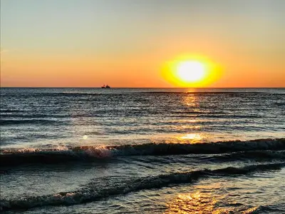 a sunset over the ocean with a boat in the distance at Canal House - Homestay in Alkmaar