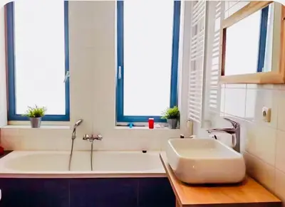 a bathroom with a tub and a sink and windows at Canal House - Homestay in Alkmaar