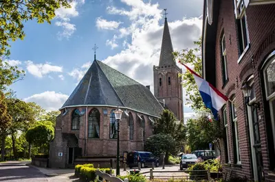 a church with a steeple and a flag on a building at B&B Appartement Hemels in Twisk