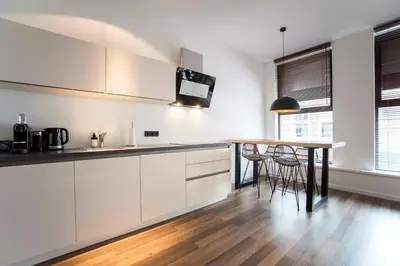 a kitchen with white cabinets and a wooden table at Sack-Time fashion boutique hotel 6 & 7 in Zandvoort