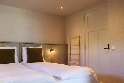 a bedroom with two white beds and a door at Hoeve te Gast - vakantieboerderij in Groet