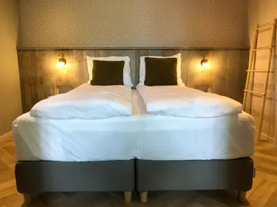 a large white bed with two pillows on it at Hoeve te Gast - vakantieboerderij in Groet