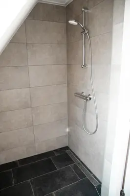 a shower with a shower head in a bathroom at Hoeve te Gast - vakantieboerderij in Groet