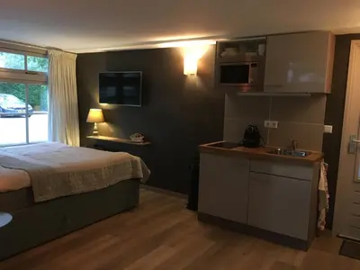 a bedroom with a bed and a kitchen with a sink at Veld en Bosch in Leusden