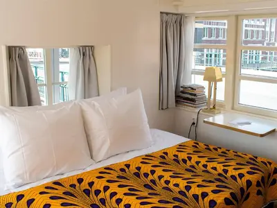 a bedroom with a bed with a black and yellow blanket at SWEETS - Van Hallbrug in Amsterdam