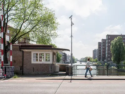 a woman walking down a street next to a building at SWEETS - Van Hallbrug in Amsterdam