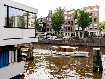 a boat floating down a river in a city at SWEETS - Hortusbrug in Amsterdam