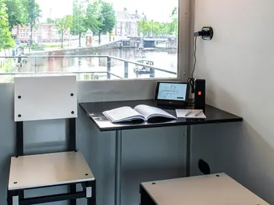 a desk with a laptop and books on it next to a window at SWEETS - Hortusbrug in Amsterdam